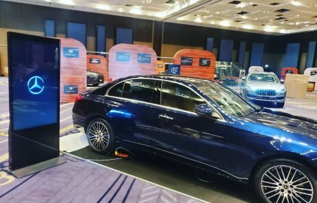Tótem digital de marca junto a auto en exhibición